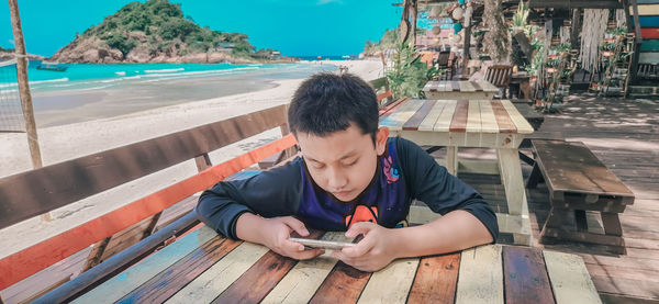 Technology and beach concept. teenage boy using smart phone mobile. summer holidays.