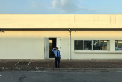 Rear view of man walking on street against building