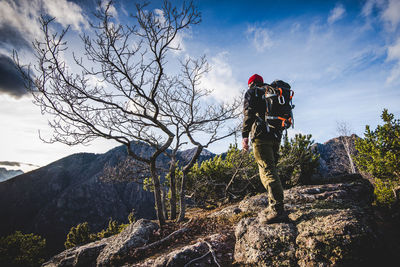 Man standing on rock against sky