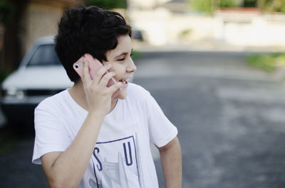 Teenage boy outdoors talking on the phone and laughing 