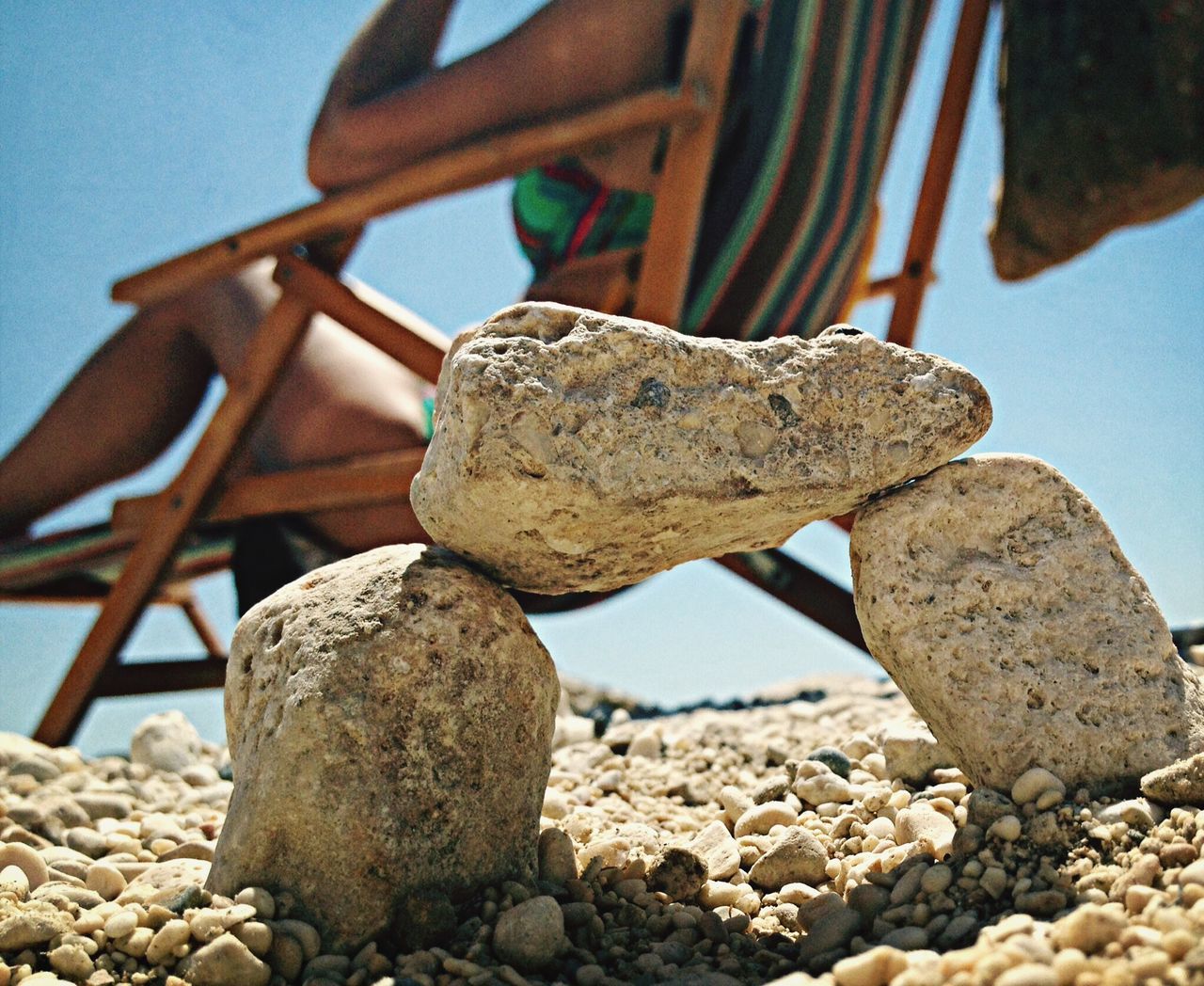 stack, rock - object, stone - object, pebble, clear sky, beach, blue, balance, sky, stone, sunlight, close-up, sea, textured, focus on foreground, nature, large group of objects, wood - material, rock, log