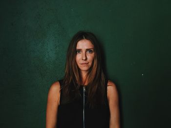 Portrait of young woman standing against white background