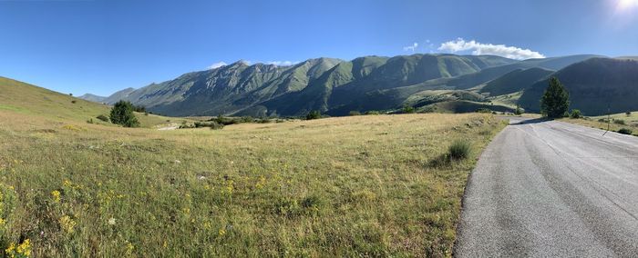 Scenic view of landscape and mountains against blue sky