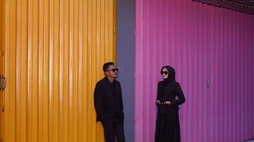 Young couple standing against wall