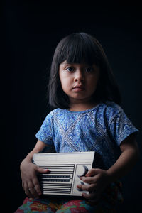 Portrait of cute girl against black background