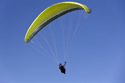 Low angle view of person paragliding against clear sky