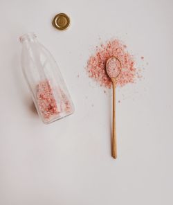 Pink sea salt for bath in wooden spoon and bottle self-care moments