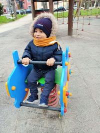 Full length of boy sitting on slide at playground