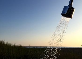 Close-up of water drops on grass against clear sky