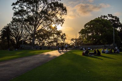 People in park against sky during sunset