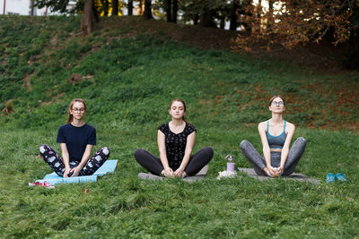 The relaxed girls is doing yoga in the park on carpet