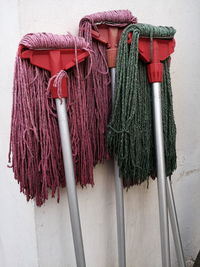 Close-up of colourful mops against wall