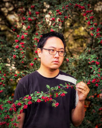 Midsection of man holding rowan berry branch against rowan trees in woods.