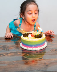 Little girl is blowing candles on her birthday cake. celebrating at home during quarantine.