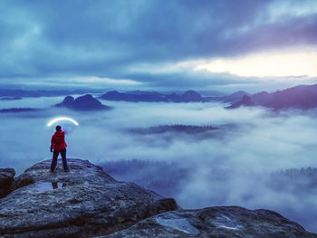 Girl on top of mountain holding strong light up her head and lightning to darkness. woman life