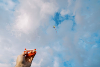 Low angle view of woman holding mobile phone against sky