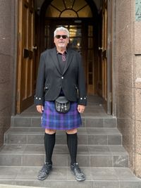Portrait of young man standing against building