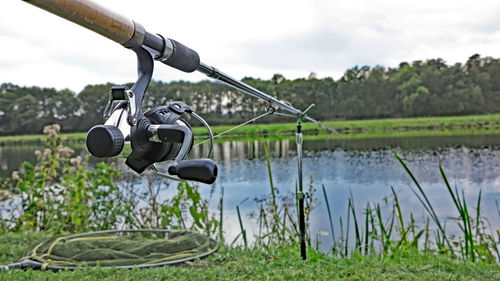 Close-up of sunglasses on field by lake against sky