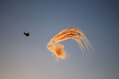 Low angle view of airshow during sunset