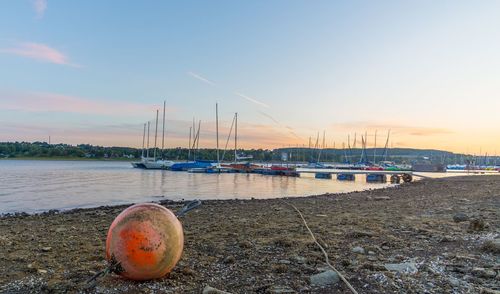 Sailboats moored on beach against sky during sunset