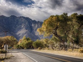 Road by trees and mountains against sky