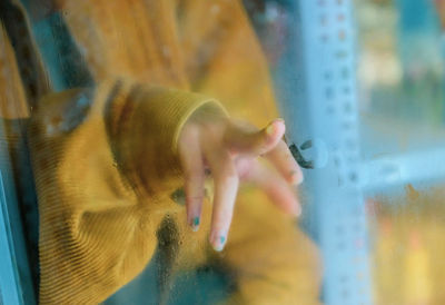 Midsection of woman touching glass window