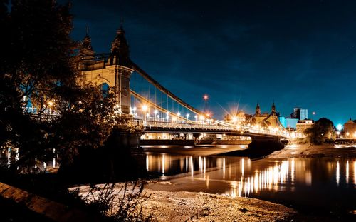 Illuminated bridge over river at night