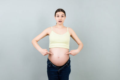 Portrait of young woman standing against white background