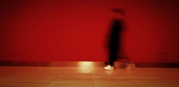 Low section of man standing by red wall