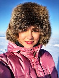 Portrait of smiling young woman standing on snow covered field 