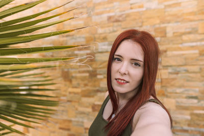 Portrait of young woman standing against wall