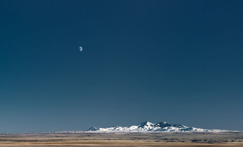 Scenic view of snowcapped mountains against clear blue sky