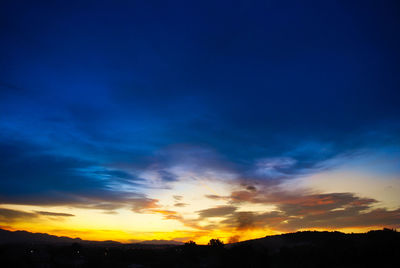 Silhouette landscape against dramatic sky during sunset