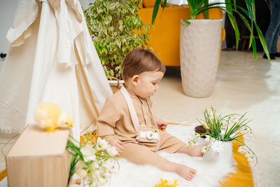 Baby playing at home on the floor tent and flowers spring