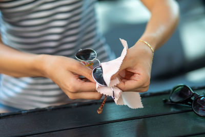 Midsection of woman cleaning sunglasses