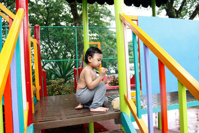 Full length of boy sitting on slide at playground