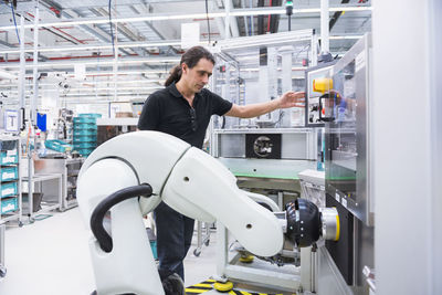 Man with assembly robot in factory