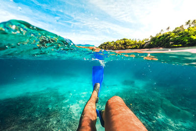 Low section of man swimming in sea against sky