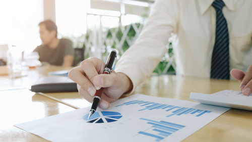 Midsection of man holding paper on table