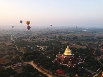 Hot air balloons over pagoda against sky