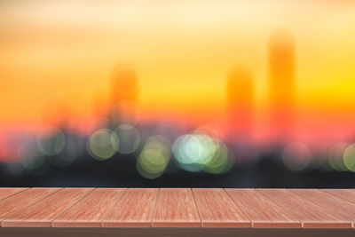 Defocused image of illuminated lights on table against sky during sunset