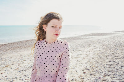 Beautiful woman standing on beach against sky