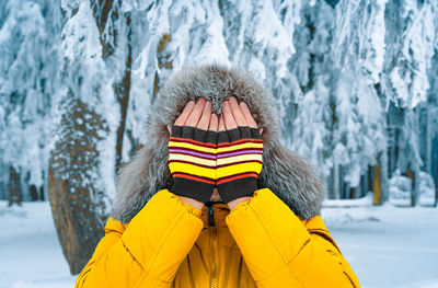 Man with fur hat and mittens in winter forest