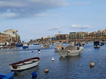 Boats moored in sea against buildings in city