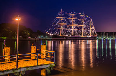 Illuminated bridge over river at night