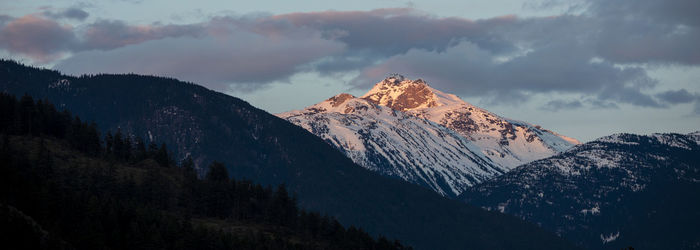 The sun sets on snow covered mountains on a spring day in the coast mountains of british columbia.