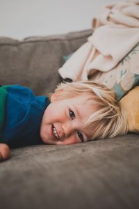 Portrait of smiling boy lying on sofa at home