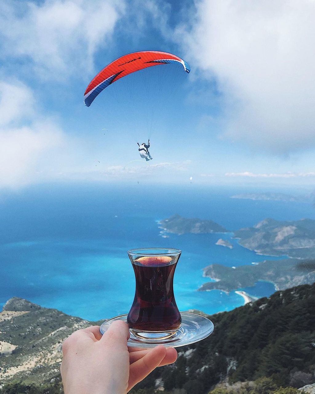 adventure, leisure activity, flying, paragliding, one person, nature, air sports, sports, extreme sports, sky, windsports, mid-air, mountain, cloud, lifestyles, water, environment, holiday, day, vacation, parachute, trip, scenics - nature, landscape, joy, beauty in nature, parachuting, transportation, motion, exhilaration, activity, outdoors, mountain range, land, holding, adult, gliding, sea, travel destinations, risk, recreation, outdoor pursuit, hand, fun, travel, air vehicle
