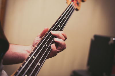 Cropped hands of man playing bass guitar
