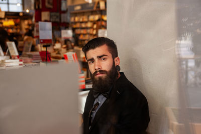 Young businessman taking a break in a cafe - view through shop young taking a break in a cafe